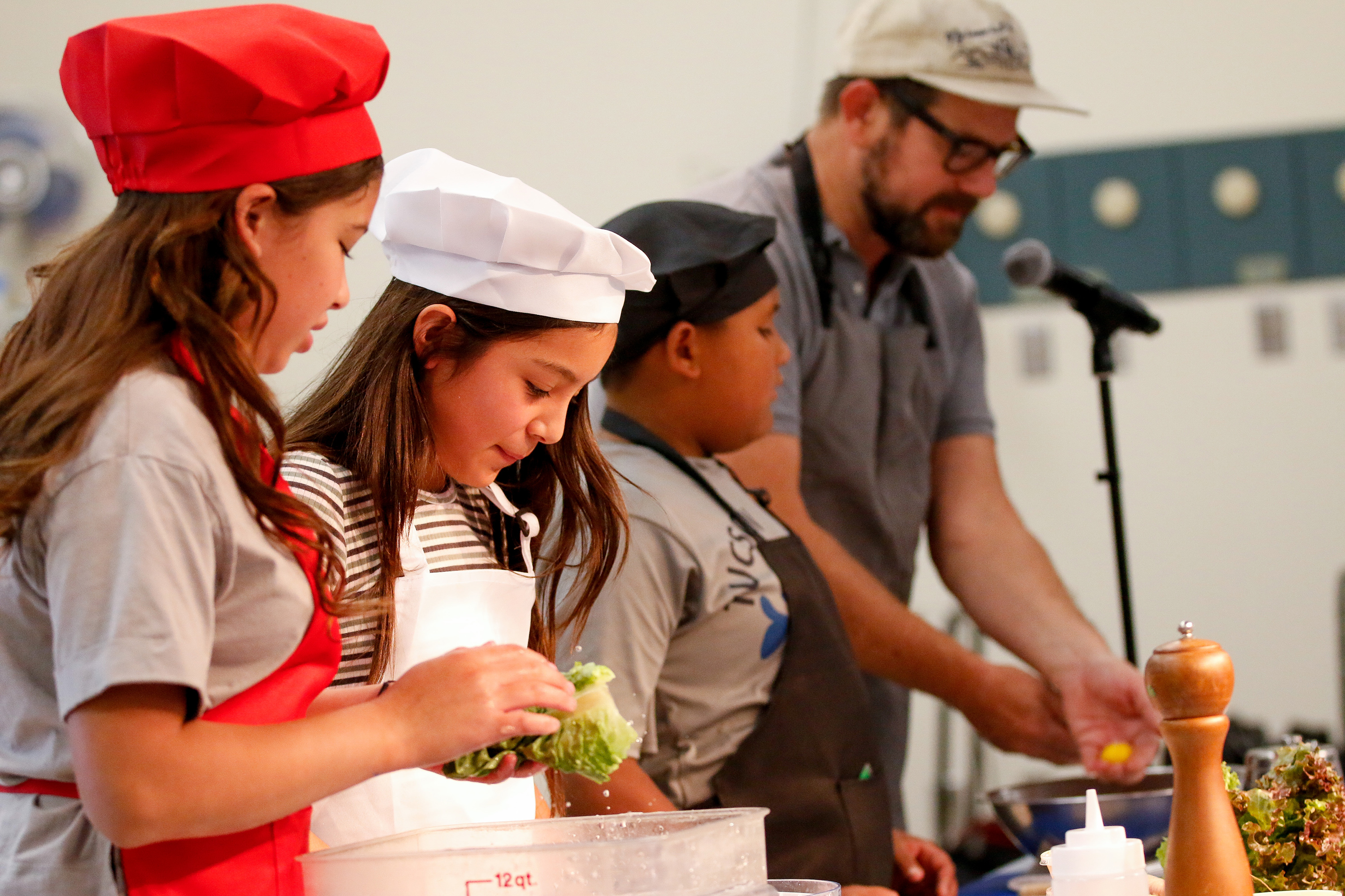 Three students listen to the chef for instructions