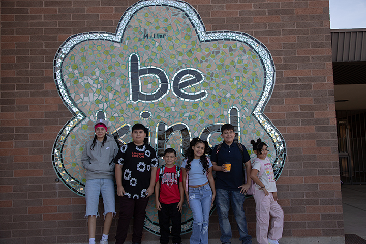 A group of students pose in front of the Be Kind mural