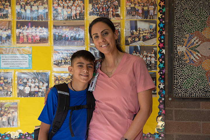A boy and his mom pose in front of a wall of photos