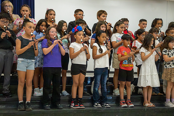 Students play recorders on stage