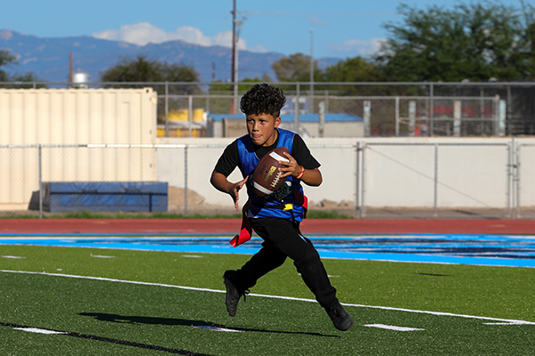 A boy runs with a football down the field