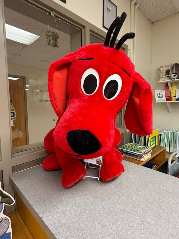 Clifford the Big Red Dog stuffed animal on top of a bookshelf