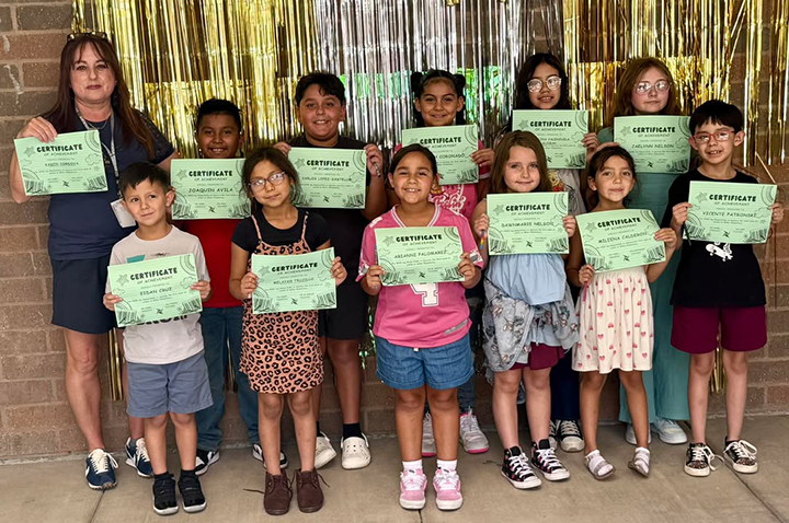 Students standing in two rows hold up awards certificates